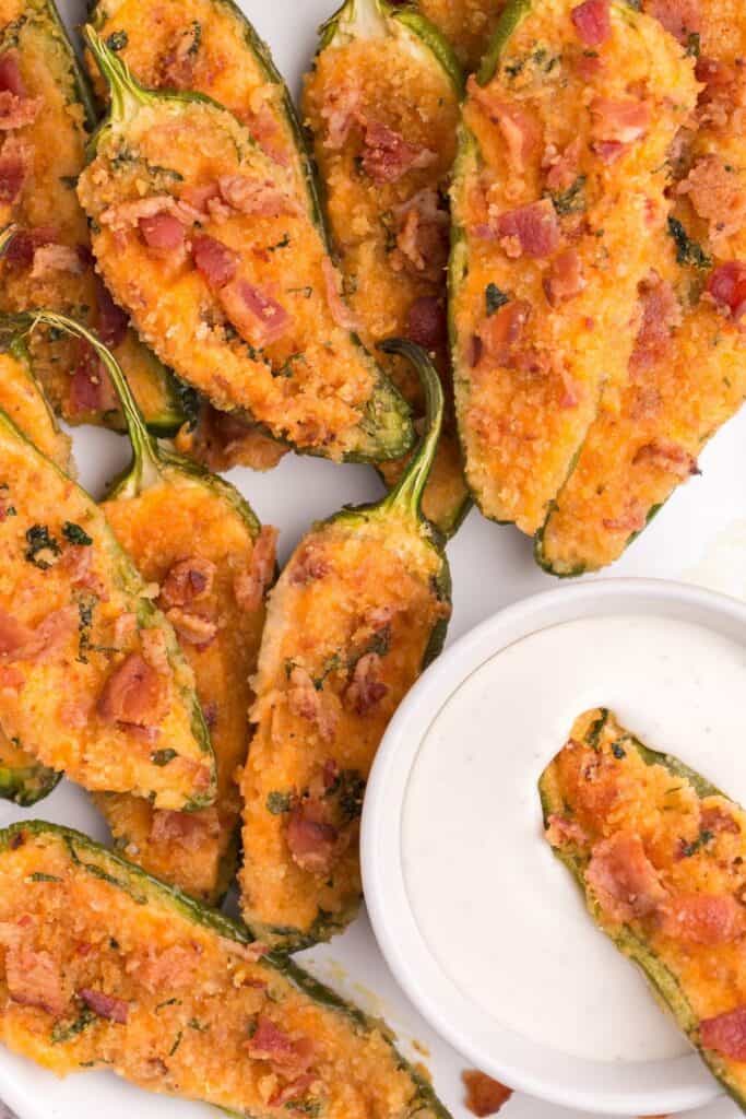 Cream cheese jalapeno poppers on a plate served alongside some ranch.