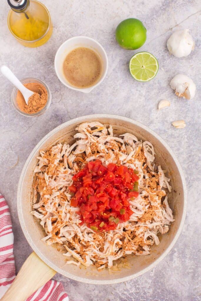 adding shredded chicken with rotel and taco seasoning to skillet 