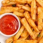 Air fryer fries on a white plate with ketchup.