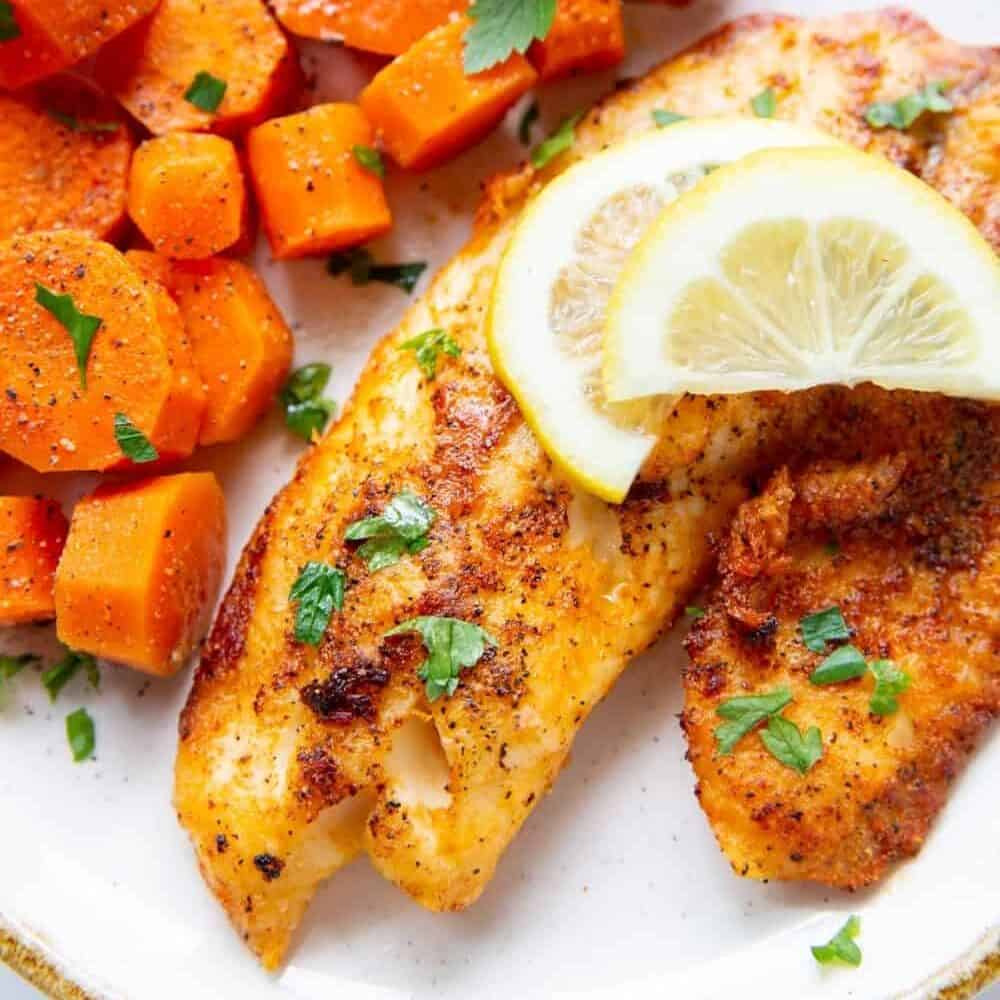 Air Fryer Tilapia with lemon sliced on top served with cooked chopped carrots