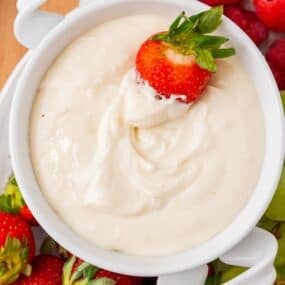 Cream cheese fruit dip with a strawberry dipped into it.