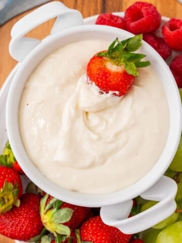 Cream cheese fruit dip with a strawberry dipped into it.