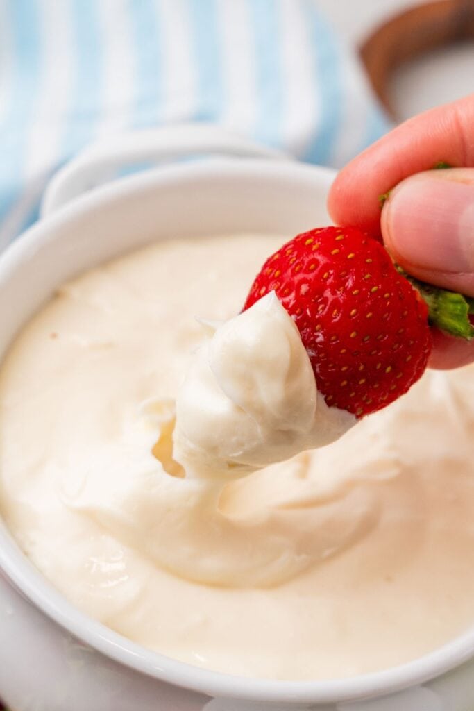 Close up of the easy fruit dip with a strawberry being dipped into it.