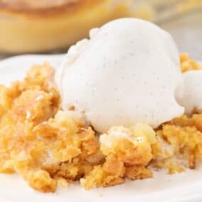 Pineapple Dump Cake on plate with scoop of vanilla ice cream.