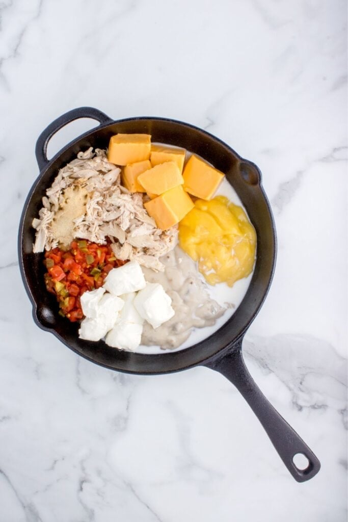 Cheese ingredients in a cast iron skillet being melted for the cheesiness in the chicken spaghetti recipe.
