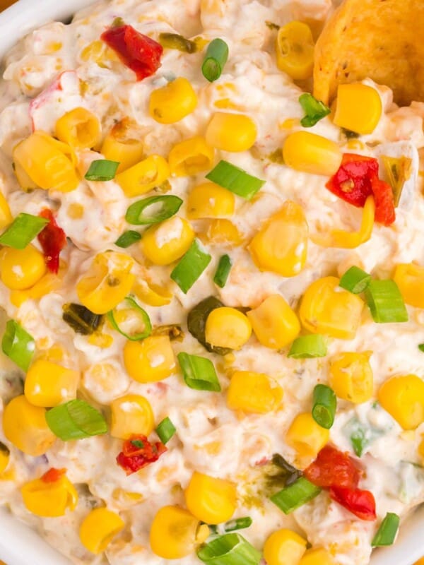 Close up view of the corn dip with fritos being dipped into it.
