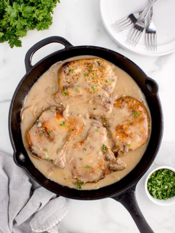 Fully cooked pork chops and gravy in a cast iron skillet.
