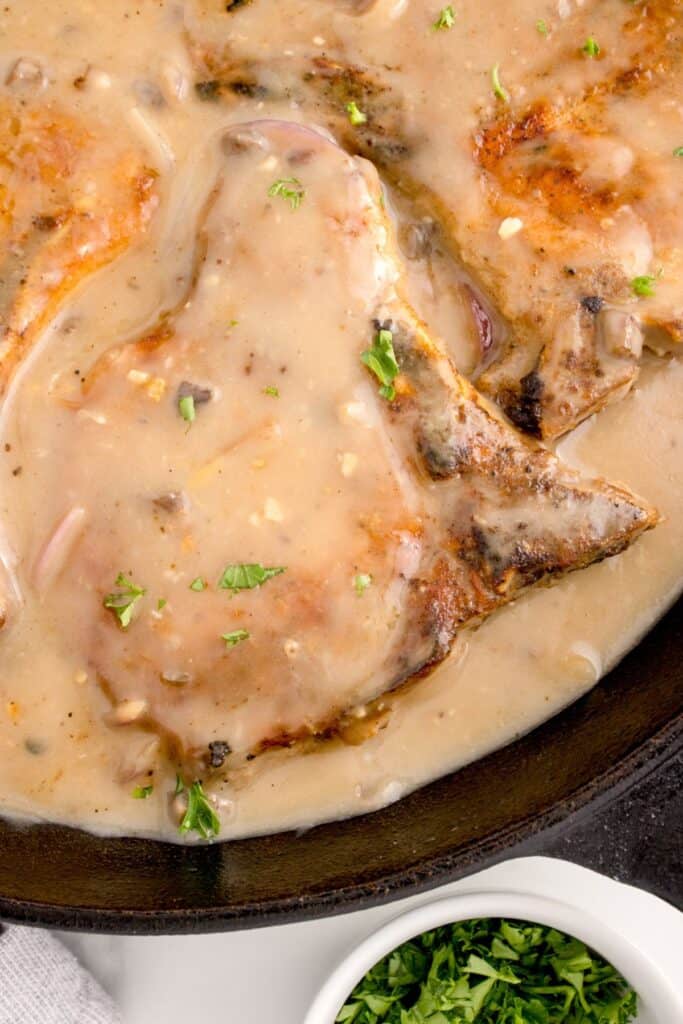 Closeup of cooked smothered pork chops in a skillet.