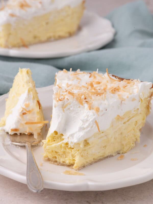 Forkful of coconut cream pie on a white plate with a cross section view of the layers of the pie.