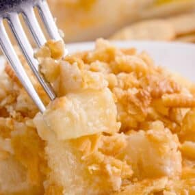 White plate with pineapple casserole and a fork.