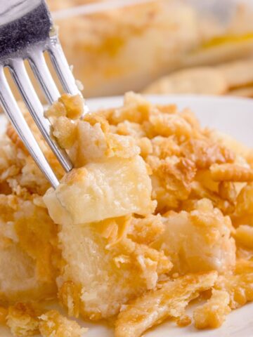 White plate with pineapple casserole and a fork.