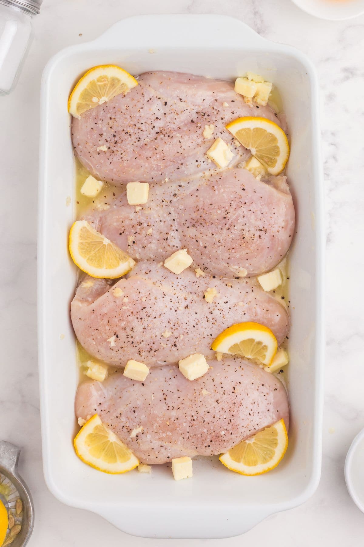 Lemon chicken recipe with butter and lemon slices about to be baked in the oven.