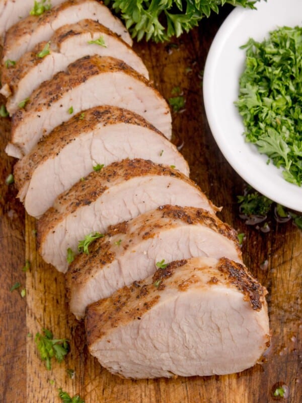 oven baked pork tenderloin sliced on a cutting board.