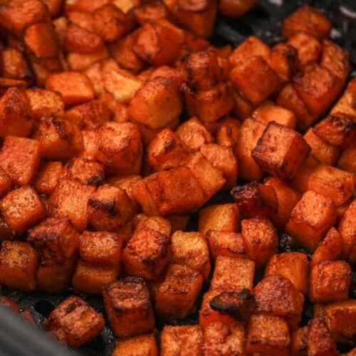 Close up of cooked butternut squash in an air fryer basket.