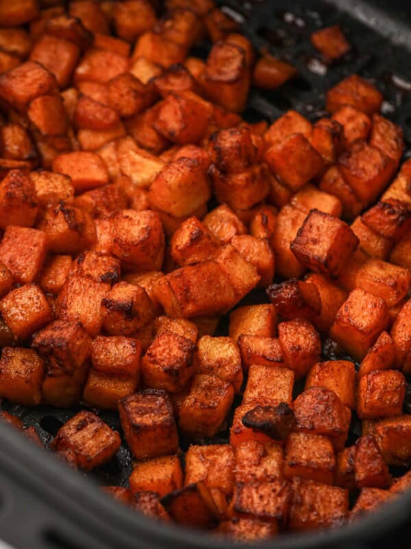 Close up of cooked butternut squash in an air fryer basket.