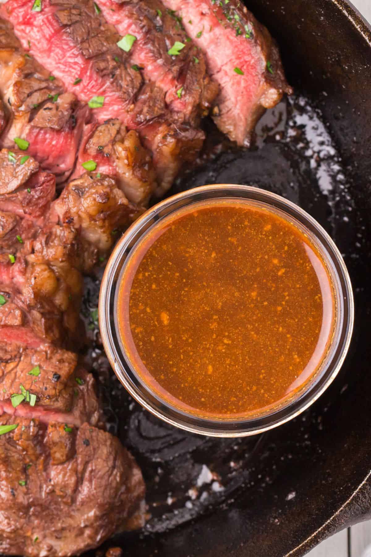 Close up of the easy steak marinade next to medium rare sliced steak.