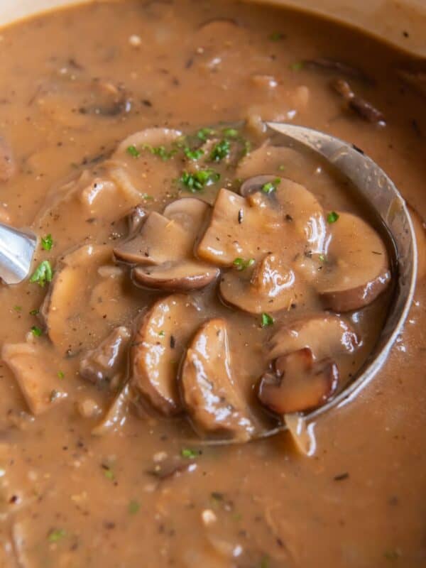 Close up of the mushroom gravy recipe in a pot with a ladle scooping it out.