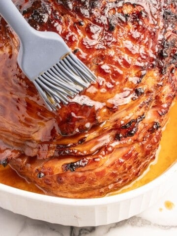 Close up of caramelized 3-ingredient ham glaze being brushed on a full ham.