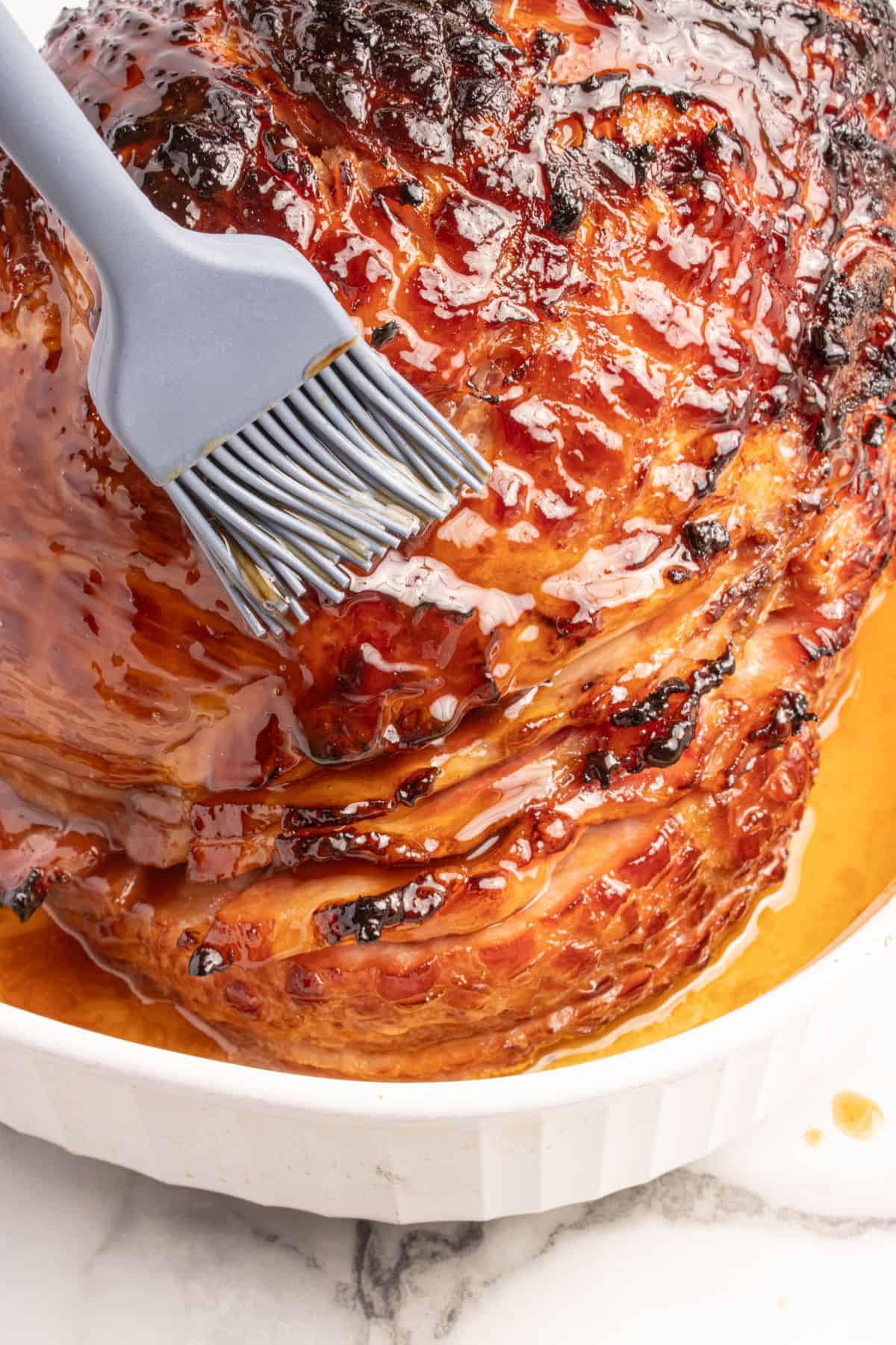 Close up of caramelized 3-ingredient ham glaze being brushed on a full ham.