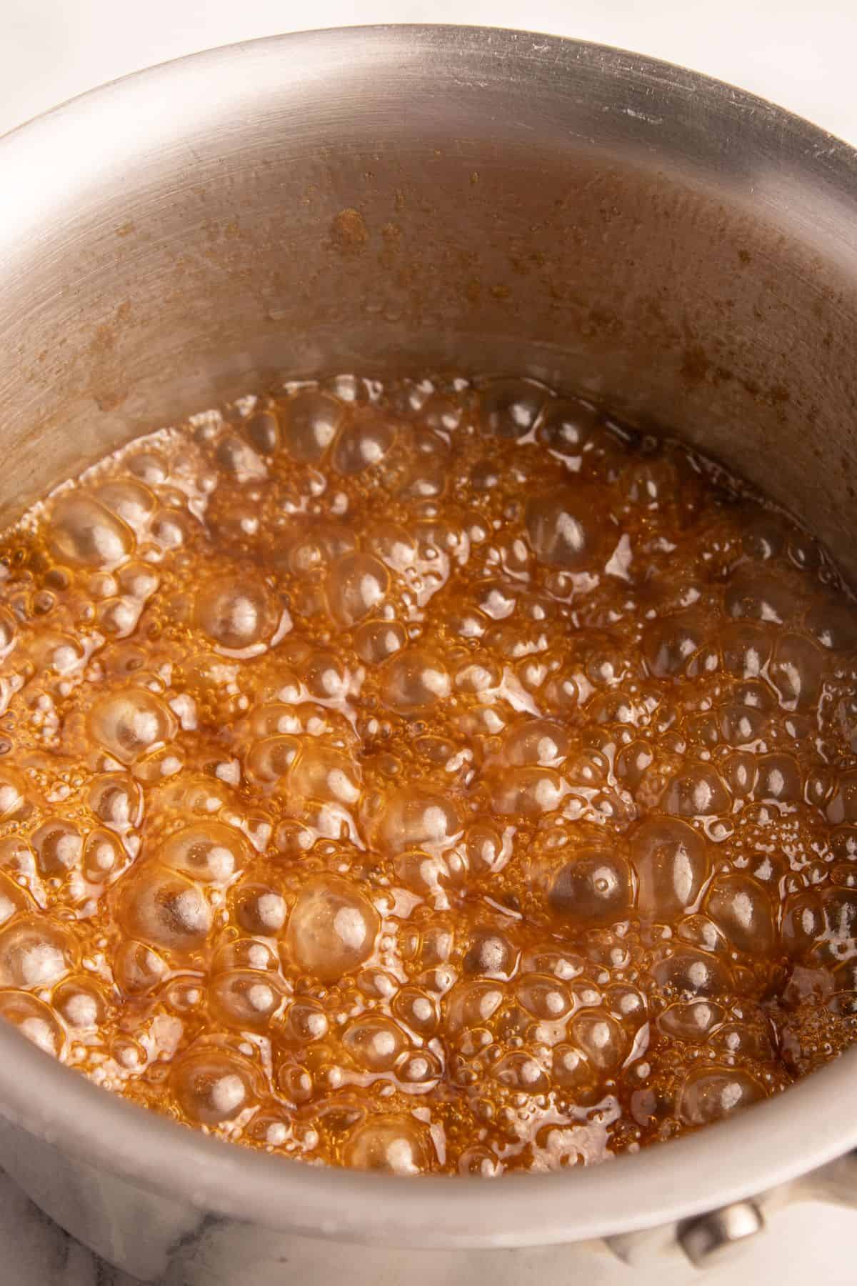 Brown sugar glaze for ham simmering with bubbles on the stove.