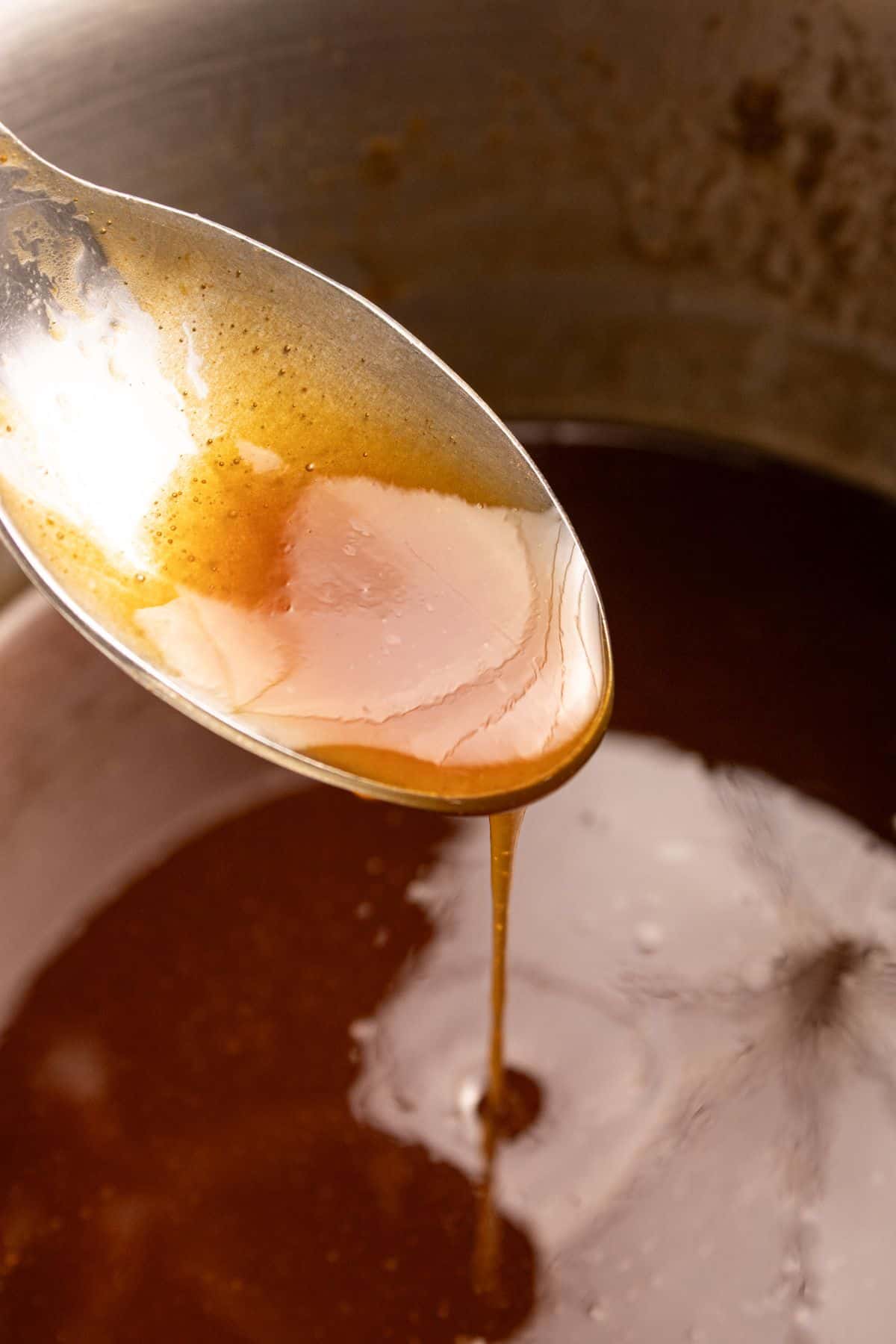 Ham glaze being picked up with a spoon to show the thickness before brushing it on a ham.