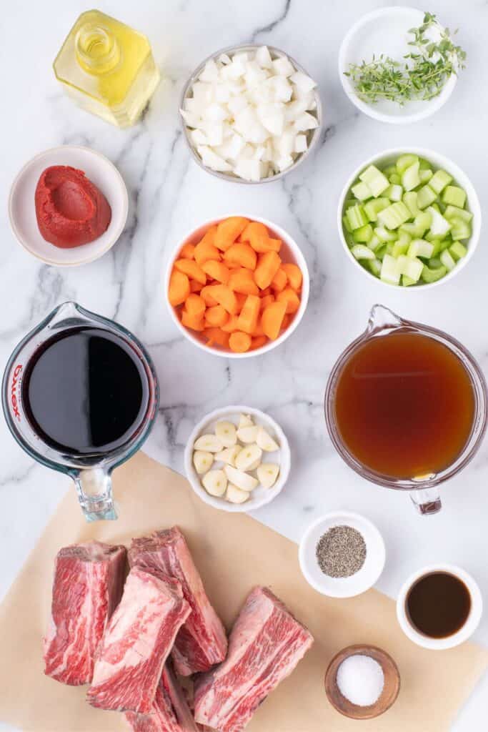 Ingredients for braised beef short ribs: beef short ribs, oil, celery, carrots, onion, garlic cloves, tomato paste, worcestershire sauce, red wine, beef stock, thyme sprigs, salt & pepper