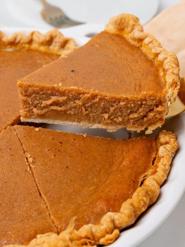 A slice of sweet potato pie being lifted from the pie dish to see the texture of the pie from the side.