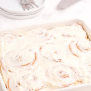 Completed and iced cinnamon rolls in a baking pan.
