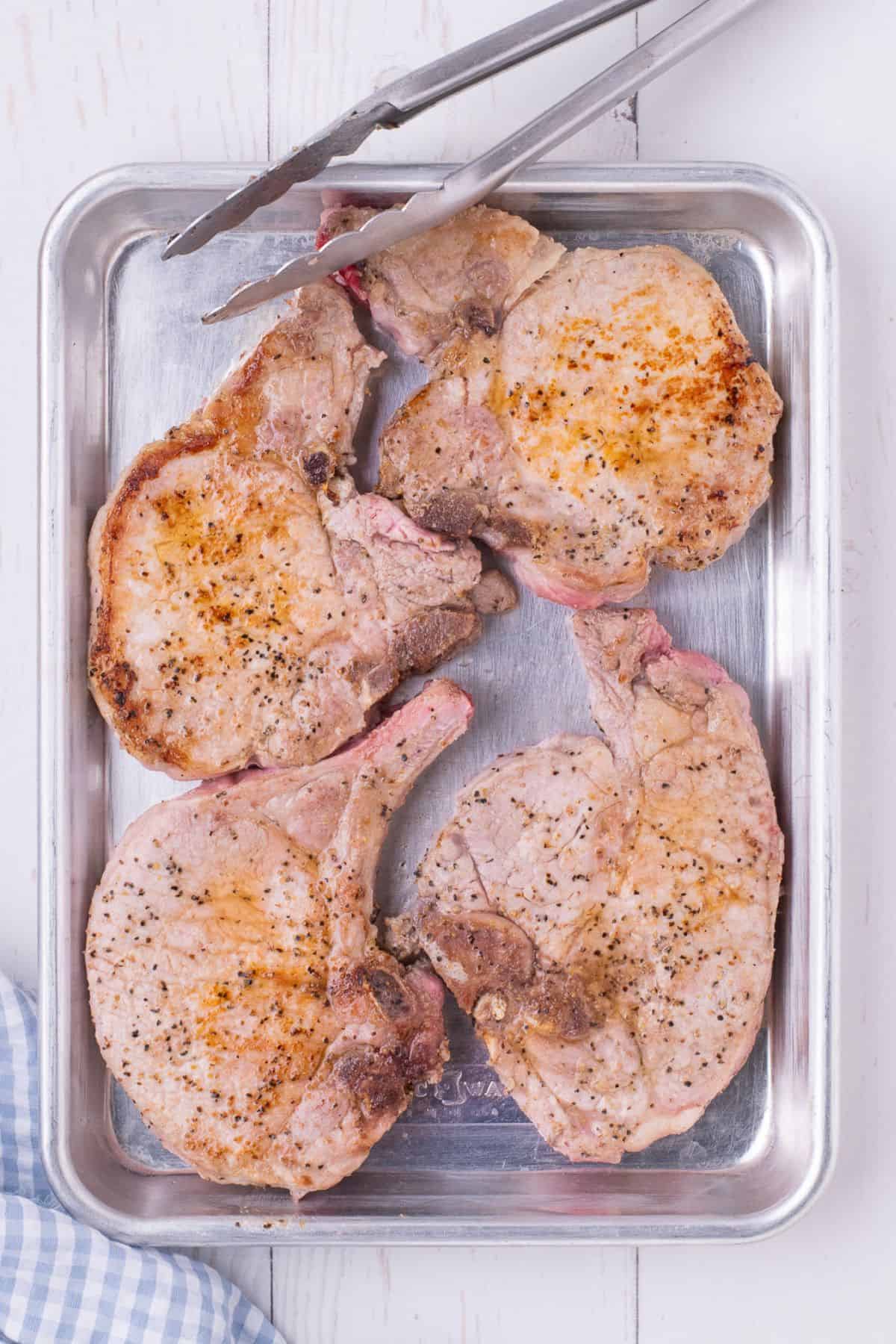 Pork chops that have been cooked in a skillet seasoned with salt and pepper.