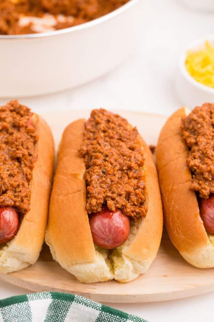 Row of hot dogs on a serving platter with homemade chili on top.