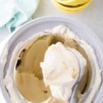 Ice cream insert bowl with homemade vanilla ice cream in it. Old fashioned scoop is lifting a serving out of the insert.