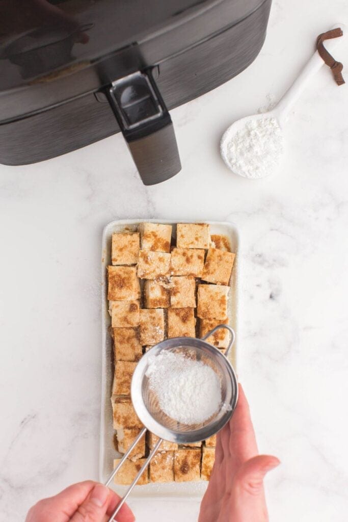 air fryer tofu having cornstarch sprinkled over it.