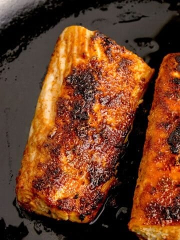 Two cooked mahi mahi fillets in a cast iron pan