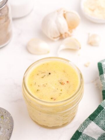 A glass jar of homemade garlic parmesan sauce.