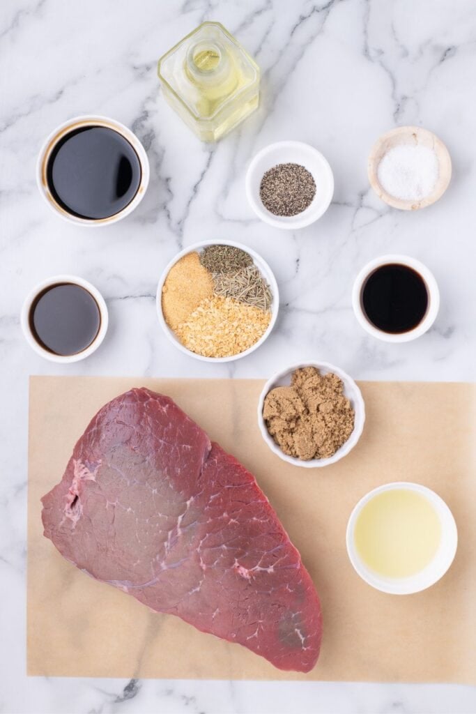 Ingredients for London broil on the grill: top round, soy sauce, balsamic vinegar, Worcestershire sauce, vegetable oil, lemon juice, brown sugar, granulated onion, garlic powder, dried rosemary, dried thyme, salt, and black pepper.