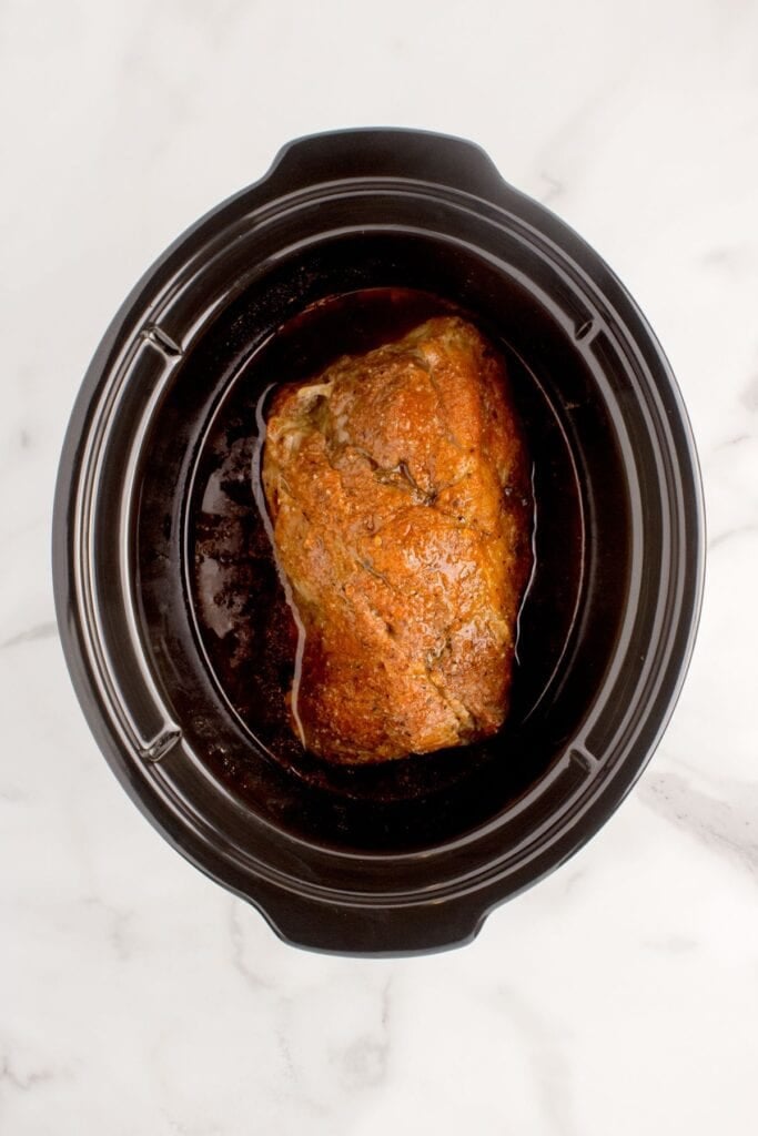 Cooked pork roast in the crock pot insert.