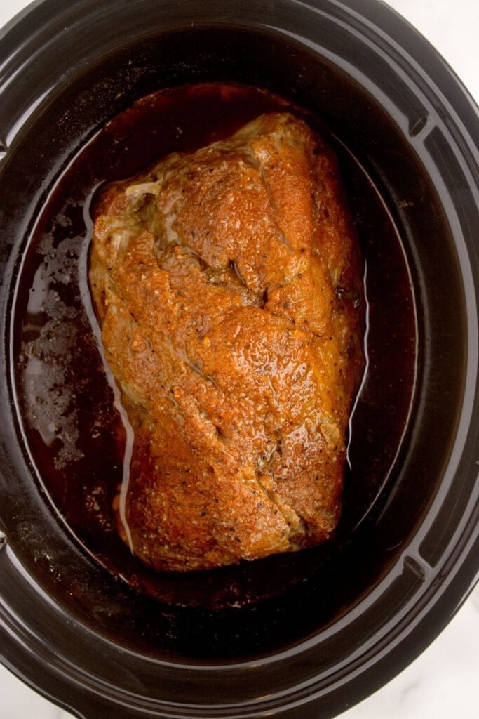 Cooked pork roast in the crock pot insert.