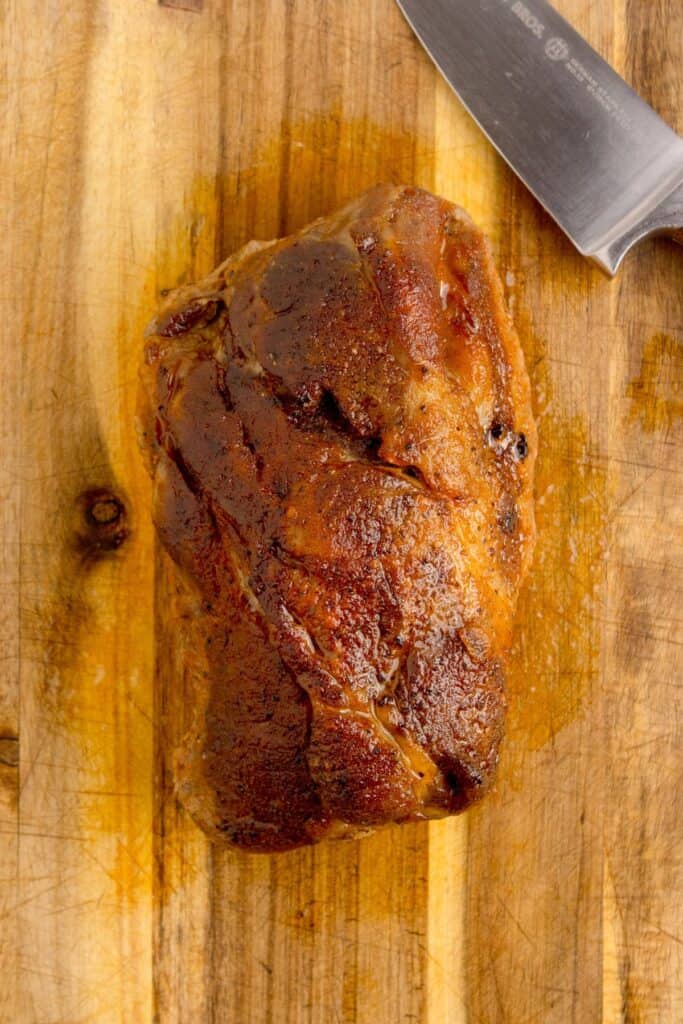 Cooked whole pork roast on a cutting board.