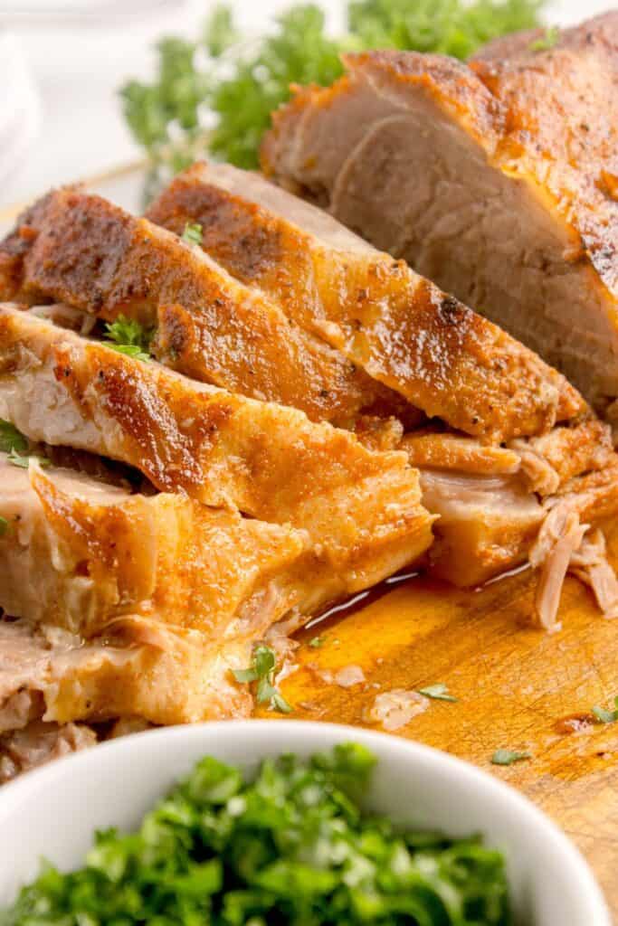 Sliced pork roast on a wooden cutting board.
