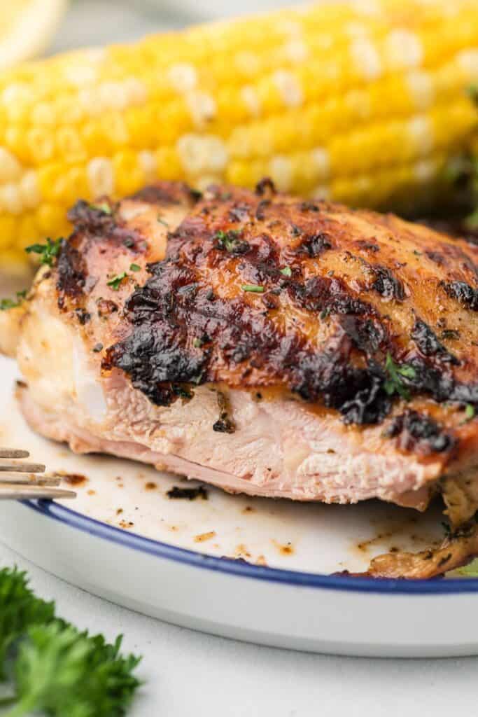 A white dinner plate with sliced grilled chicken on it to show interior of thigh.