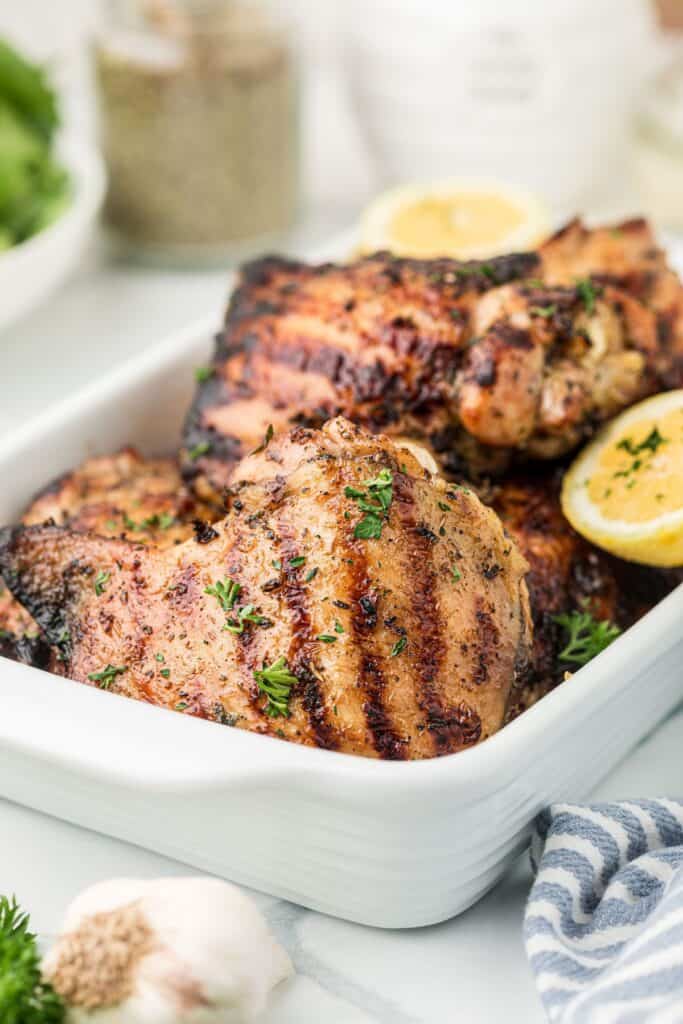 A white baking dish with chicken thighs in it.