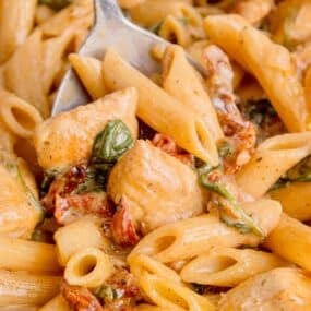 Serving spoon of chicken penne pasta.