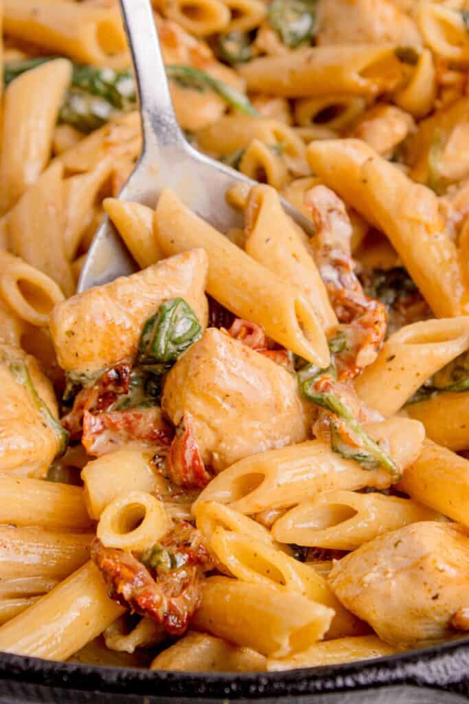 Serving spoon of chicken penne pasta.