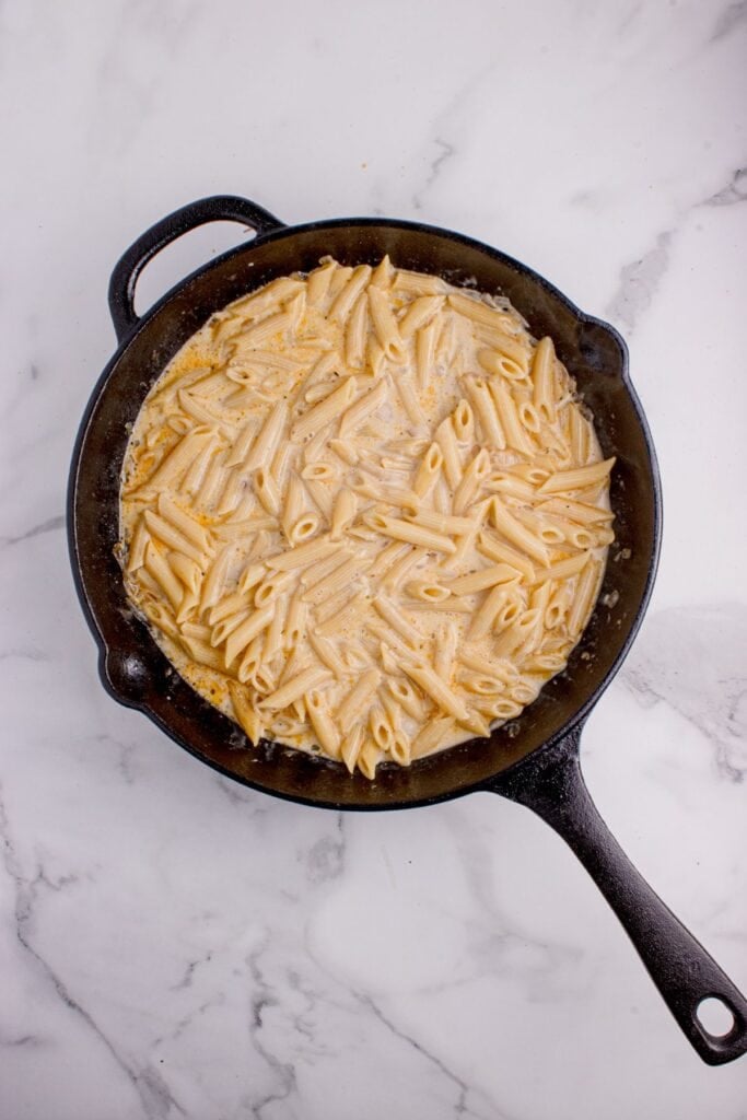 Creamy penne pasta in a cast iron pan.