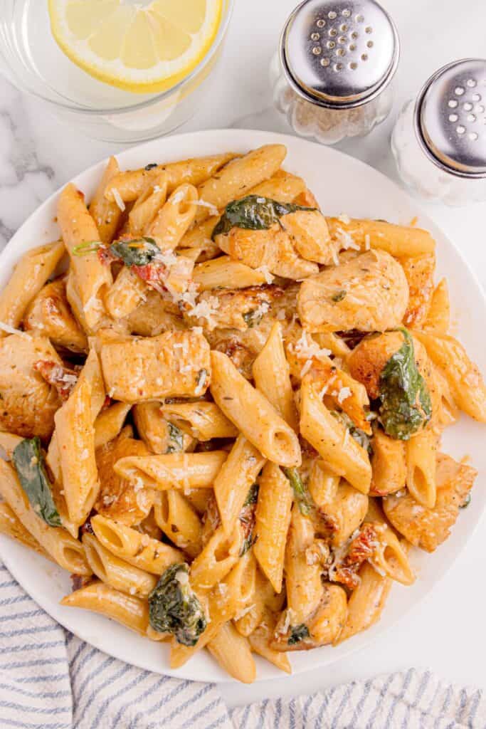 White dinner plate of penne chicken pasta.