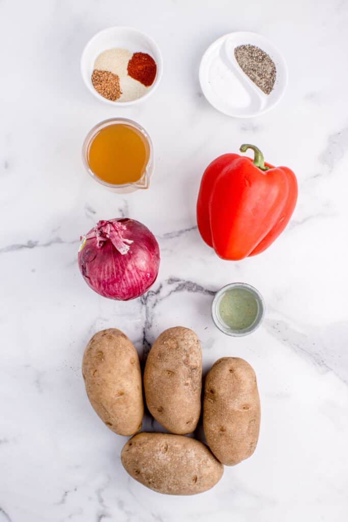 Ingredients for smothered potatoes: russet potatoes, onion, red bell pepper, vegetable oil, Cajun seasoning, smoked paprika, onion powder, garlic powder, black pepper, salt, chicken broth, and fresh parsley.