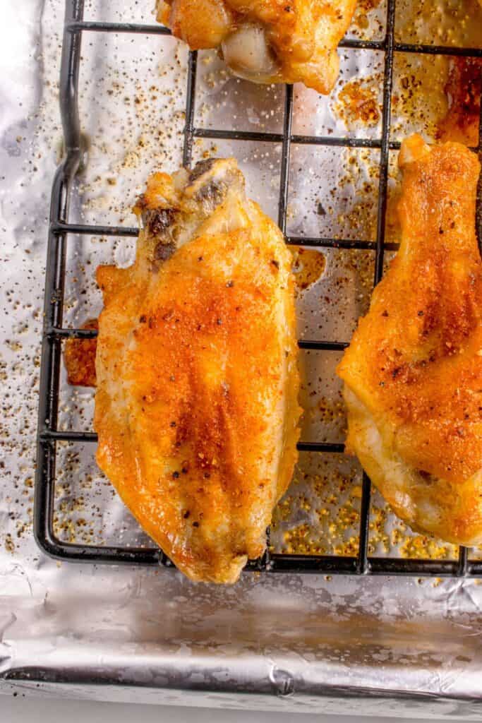 Detail view of chicken wings on a wire rack over an aluminum lined baking sheet.