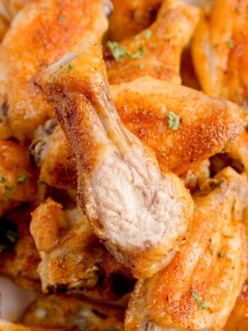 A pile of chicken wings. The top one has a bite taken out of it.