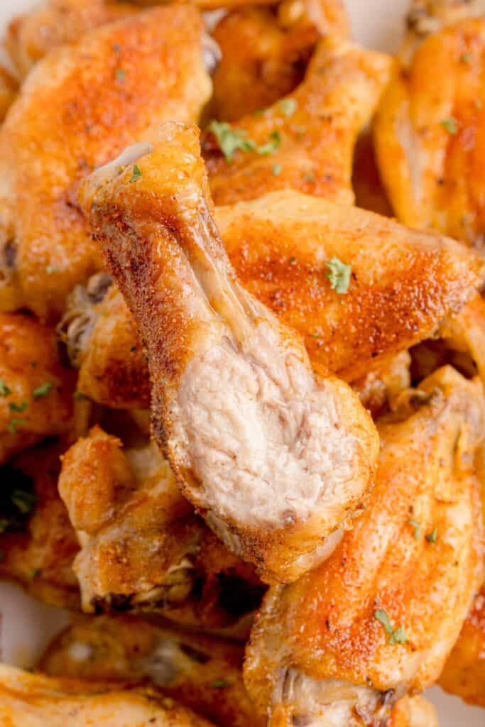 A pile of chicken wings. The top one has a bite taken out of it.