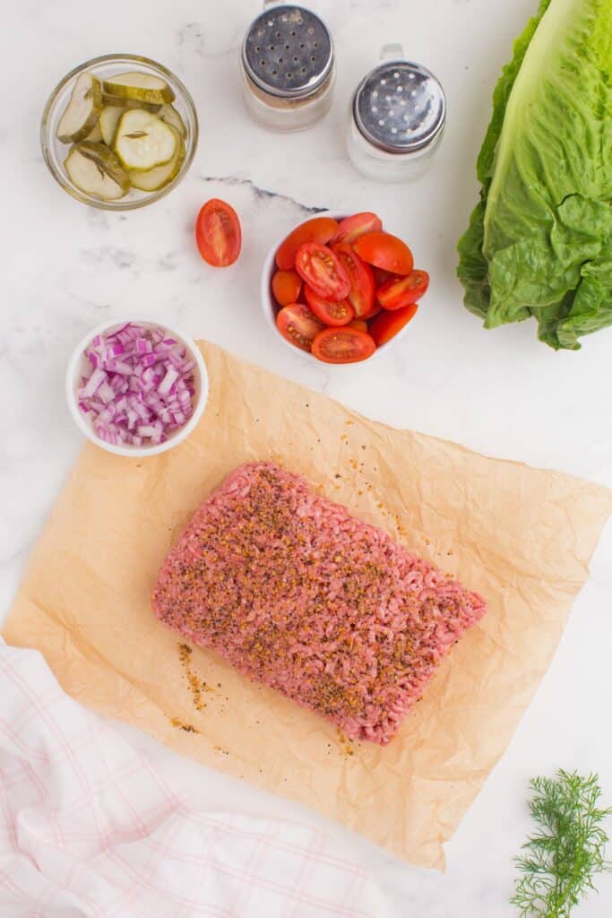 Ingredients for burger bowls: ground beef, Montreal steak seasoning, romaine lettuce, purple onion, cherry tomatoes, dill pickle chips, Fresh dill, mayonnaise, ketchup, yellow mustard, and pickle juice.